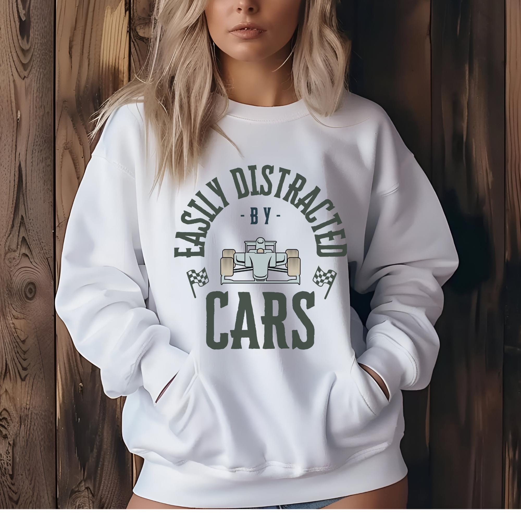 White sweatshirt with the text &#39;Easily Distracted By Cars&#39; in green lettering. A green cartoon race car is in the center of the text.