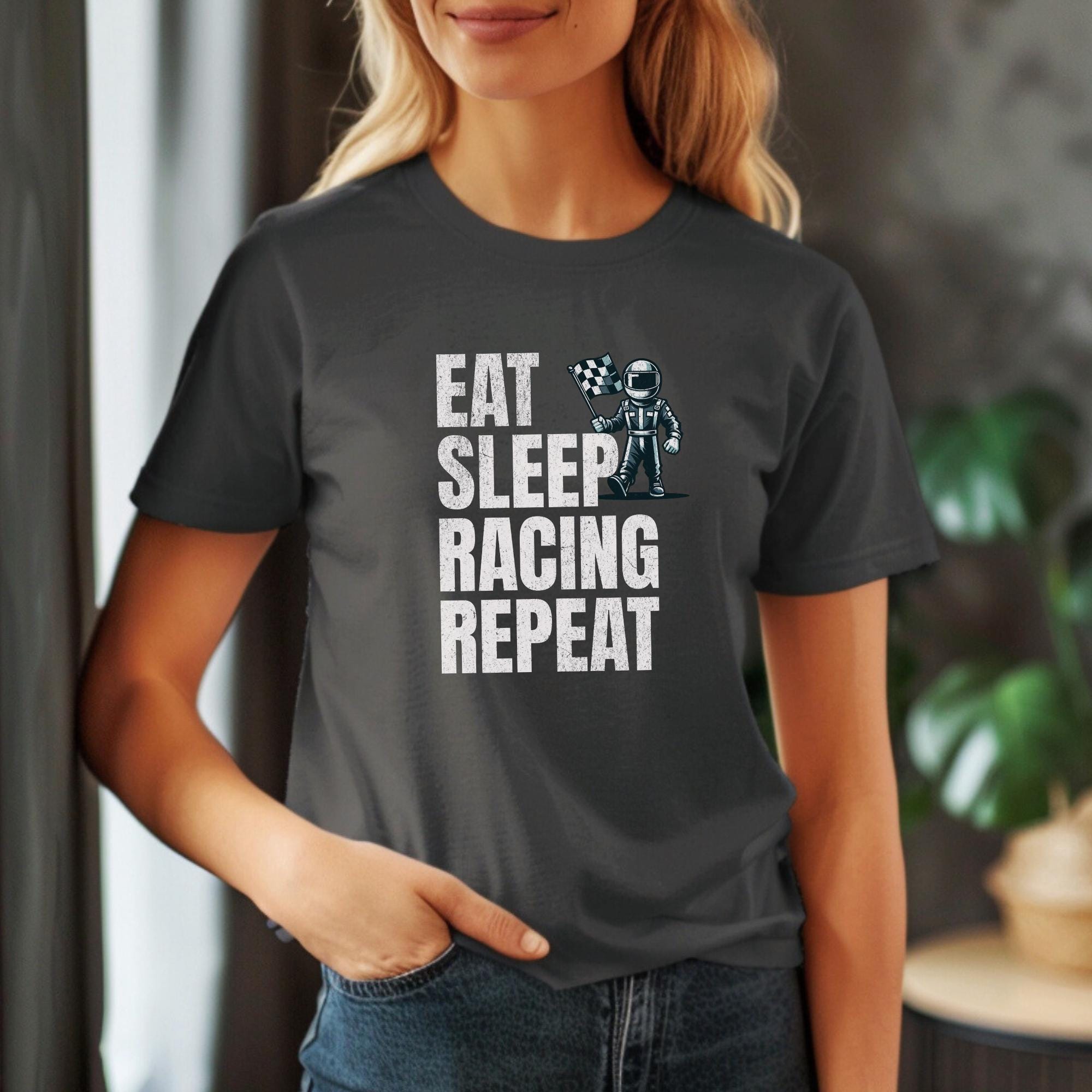 A dark gray t-shirt with the text &#39;EAT SLEEP RACING REPEAT&#39; in white. A cartoon illustration of a person in a racing suit holding a checkered flag is above the text.