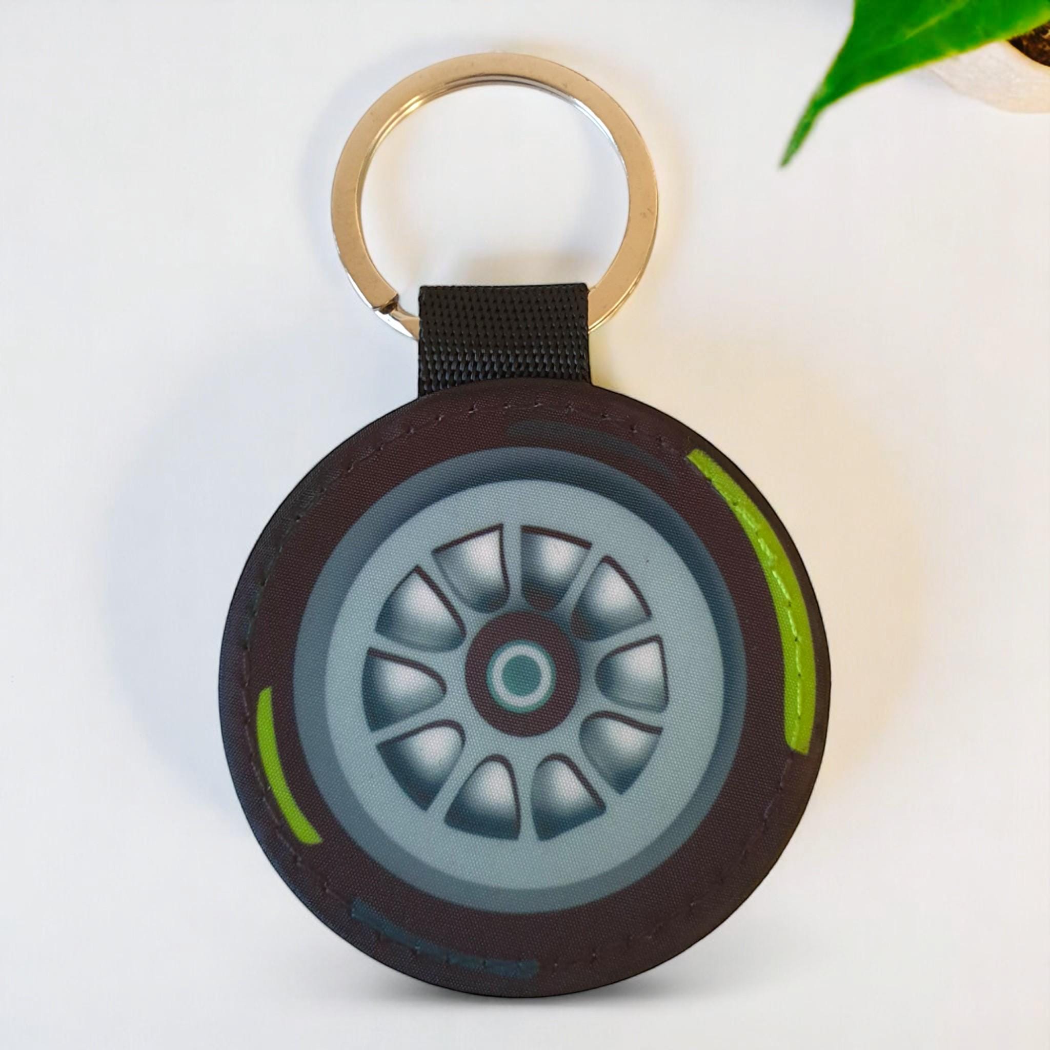 A black and yellow tire keychain with a silver rim and a silver key ring.