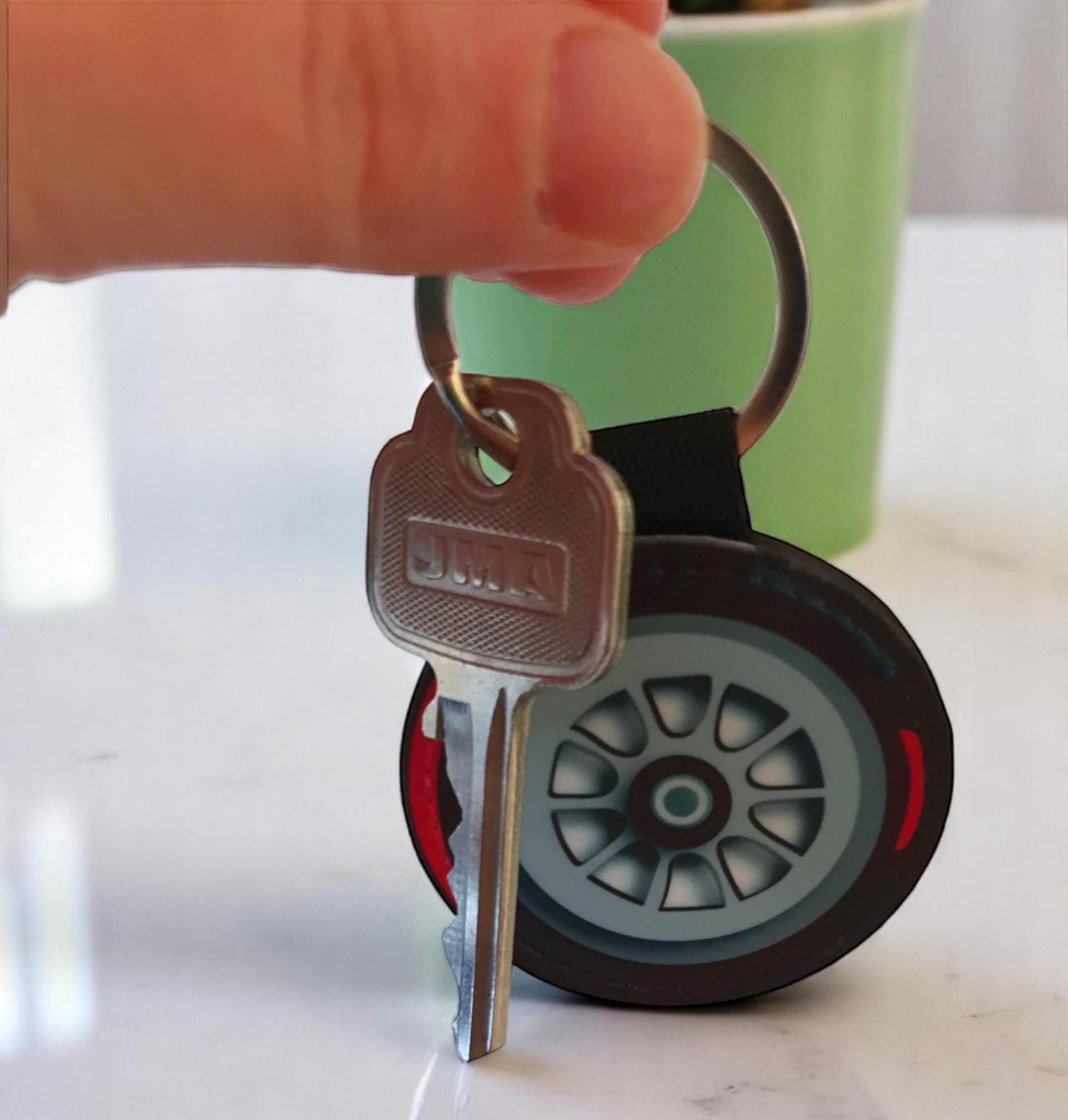 A silver key with the word &#39;SIMM&#39; on it attached to a black and red tire keychain.