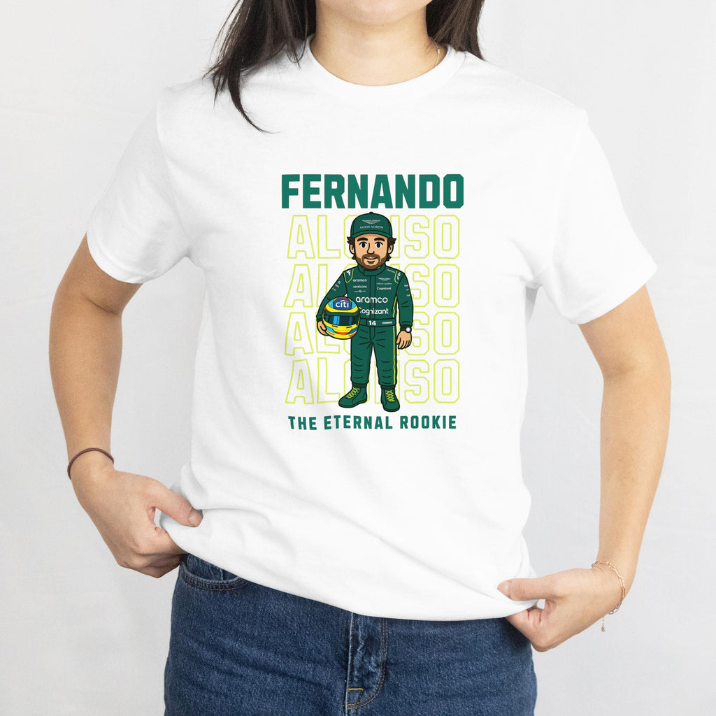 White t-shirt featuring a cartoon of a Formula 1 driver in a green racing suit and helmet, holding a helmet. The shirt has the name &#39;FERNANDO ALONSO&#39; in green block letters above the cartoon and the words &#39;THE ETERNAL ROOKIE&#39; below.