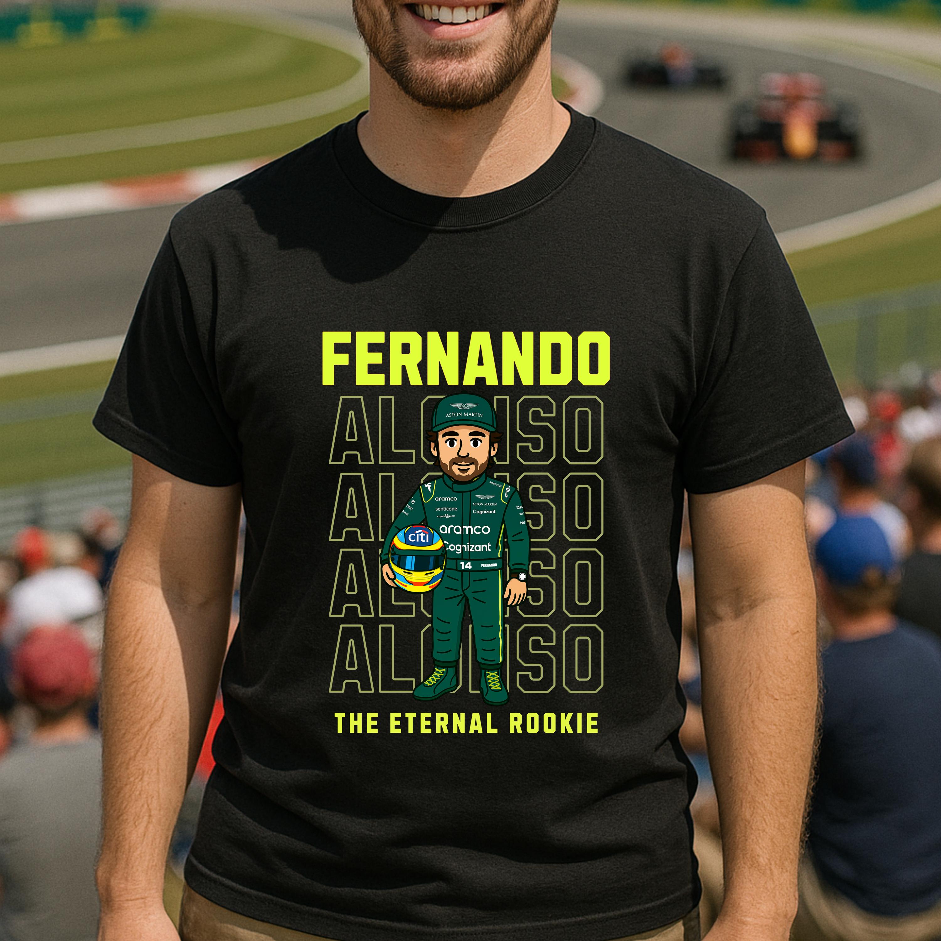 Black t-shirt featuring a cartoon of a Formula 1 driver holding a helmet. The shirt displays the name &#39;FERNANDO ALONSO&#39; in yellow, repeated multiple times. Below the cartoon, the text reads &#39;THE ETERNAL ROOKIE&#39;. The driver is wearing a green racing suit with sponsor logos.