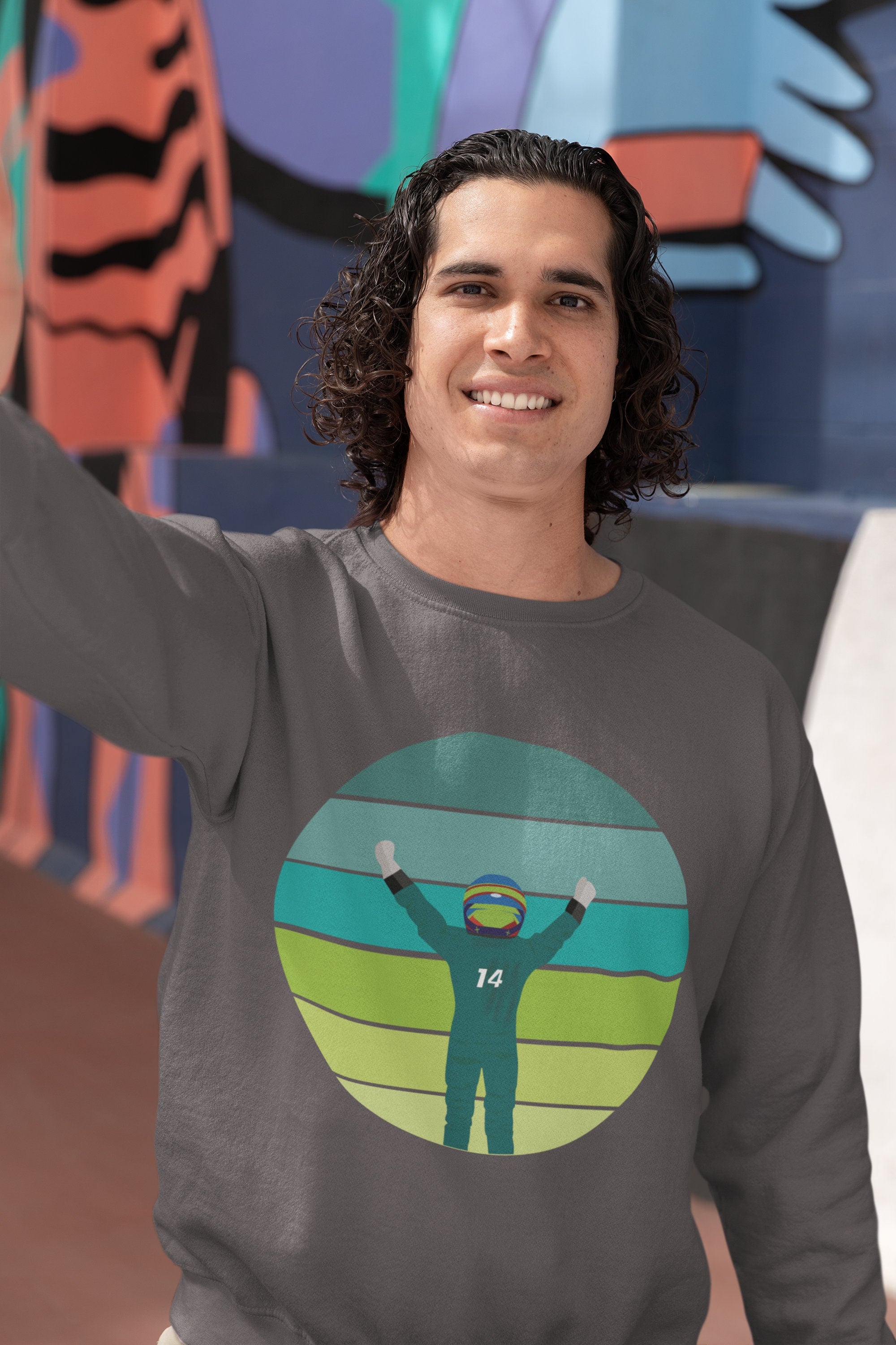 A gray sweatshirt with a circular graphic of Fernando Alonso in a racing suit with the number 14 on the front, raising their arms in celebration against a green, yellow, and blue striped background.